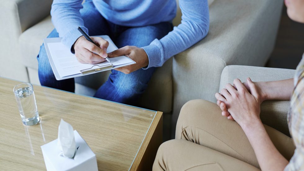 Male psychologist making notes during psychological therapy